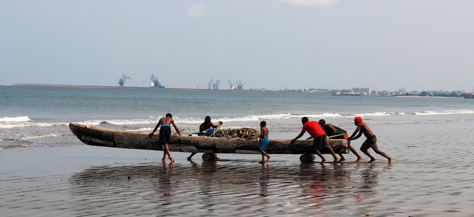 Equatorial Guinea - fishermen launching boat from beach