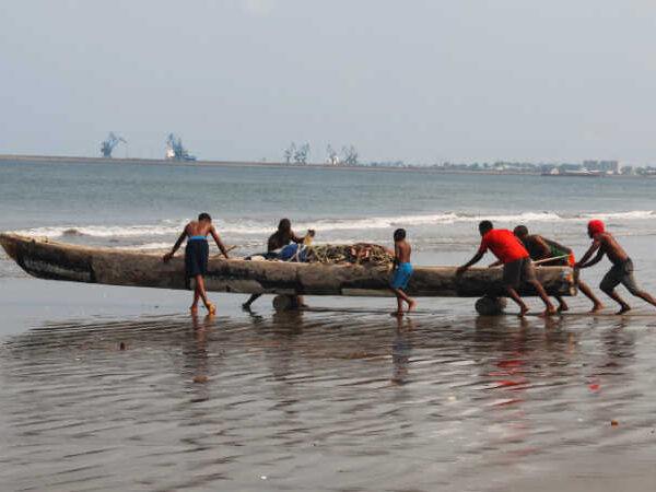 Equatorial Guinea fishermen launching boat from beach