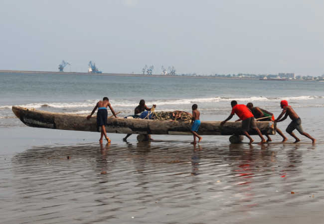 Equatorial Guinea fishermen launching boat from beach