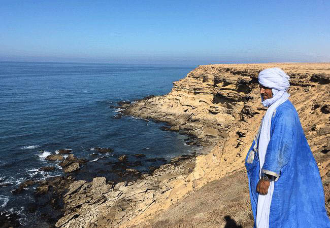 Blue robed man on cliffs overlooking the ocean - Morocco and Western Sahara Holidays and Tours