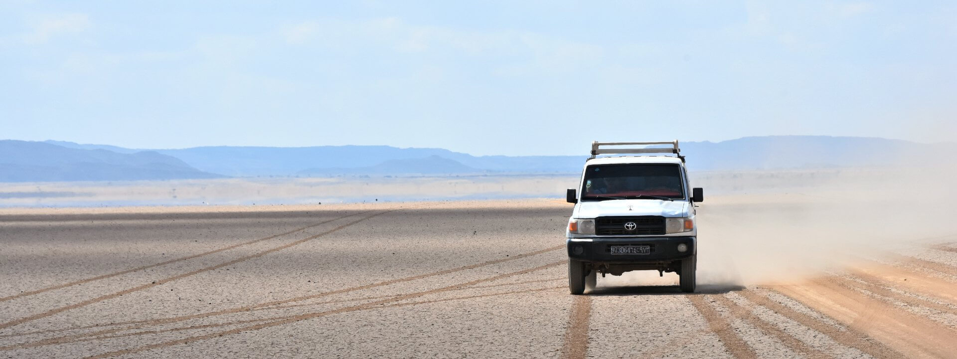 A single four-wheel drive vehicle crossing salt flats to illustrate remote holidays abroad